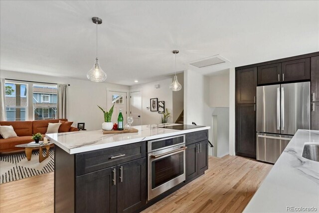 11021 Otis St, Westminster, CO 80020 - kitchen featuring stainless steel appliances, light wood-style floors, decorative light fixtures, open floor plan, and light stone counters