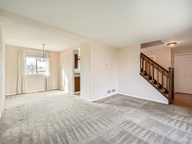 unfurnished living room featuring carpet and an inviting chandelier