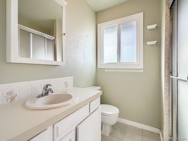 bathroom with tile patterned floors, walk in shower, vanity, and toilet