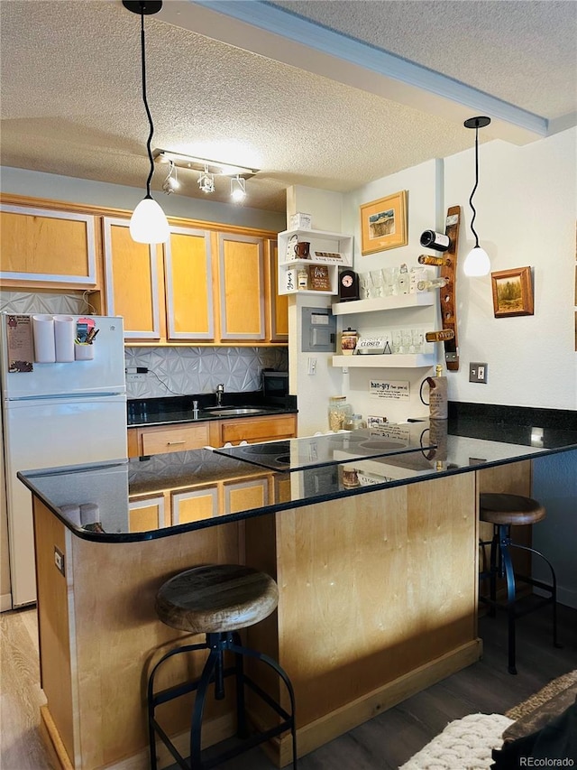 kitchen featuring light wood-style floors, freestanding refrigerator, a sink, and dark countertops