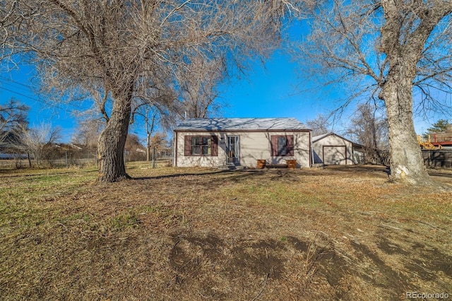 view of front of home featuring a front yard, fence, and a detached garage