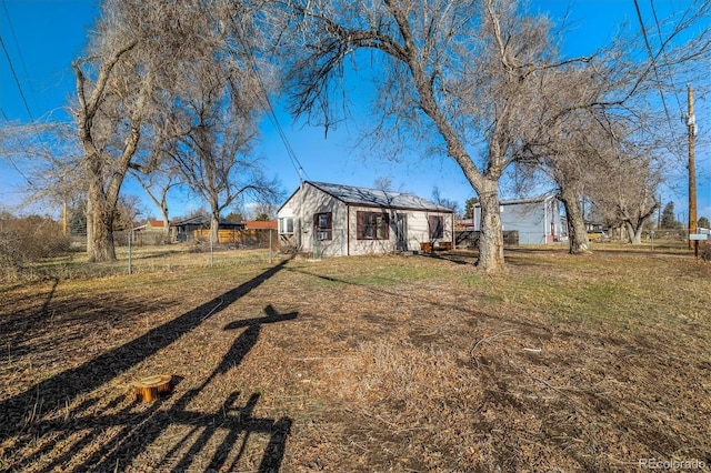 back of property featuring a lawn and fence