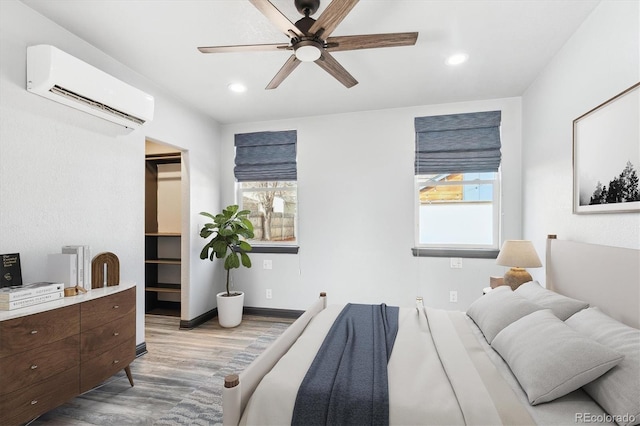 bedroom featuring a wall unit AC, multiple windows, wood finished floors, and recessed lighting