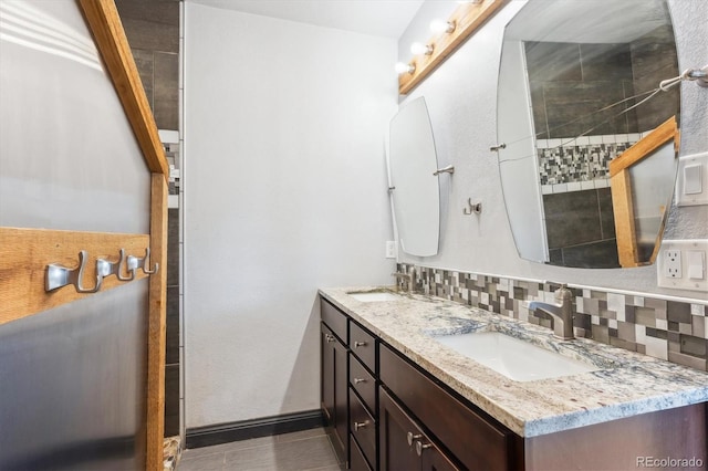 bathroom featuring decorative backsplash, double vanity, baseboards, and a sink