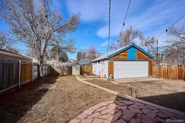 view of yard with a fenced backyard, a garage, and an outdoor structure