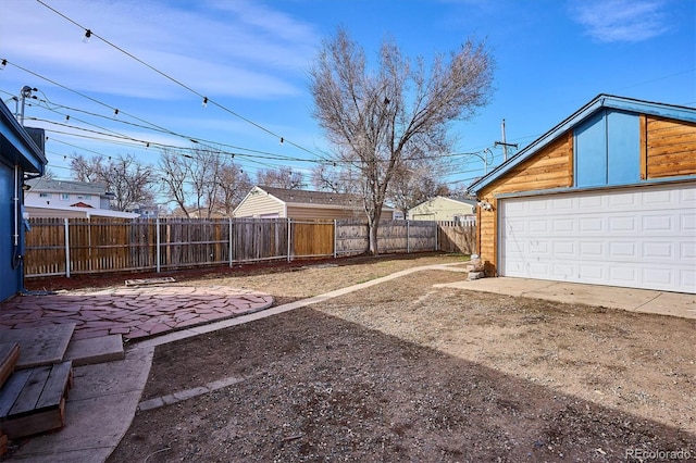 view of yard featuring a patio area, fence, and a garage