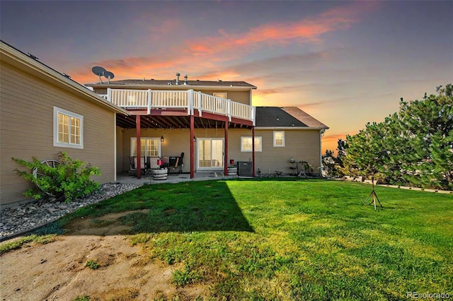 back house at dusk with a patio area, a yard, a wooden deck, and central AC unit