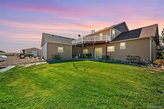 back of property at dusk with a yard, a wooden deck, and central AC unit