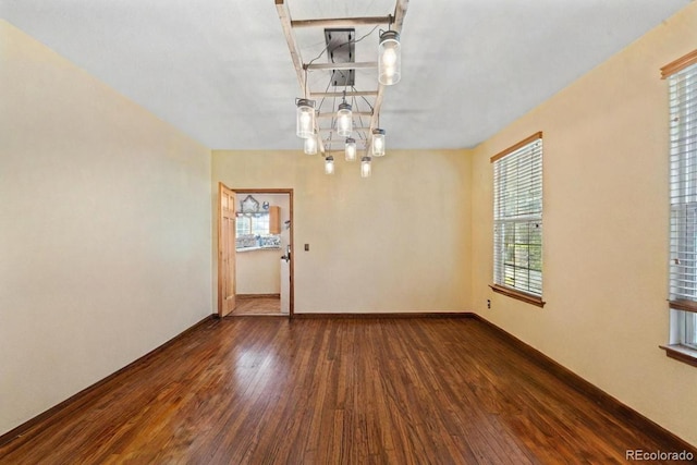 spare room with baseboards and wood finished floors