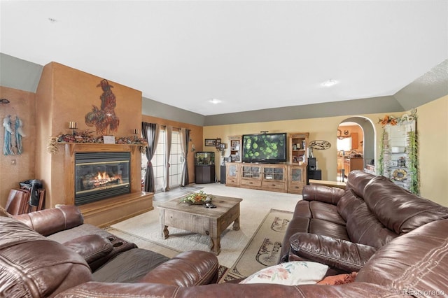 living room with arched walkways, a high end fireplace, and light colored carpet