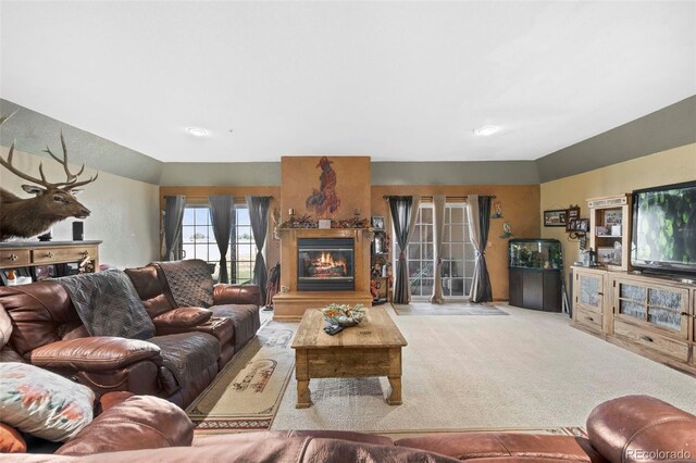 living room featuring light carpet, lofted ceiling, and a glass covered fireplace