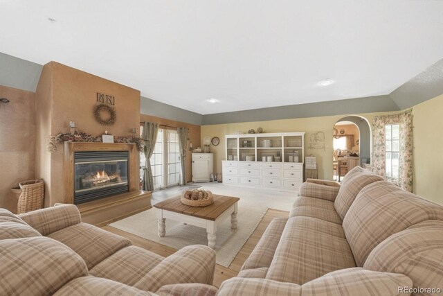 living area with arched walkways, plenty of natural light, and a premium fireplace