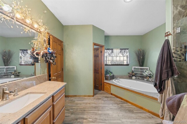 full bathroom with baseboards, wood finished floors, a garden tub, vanity, and a shower stall