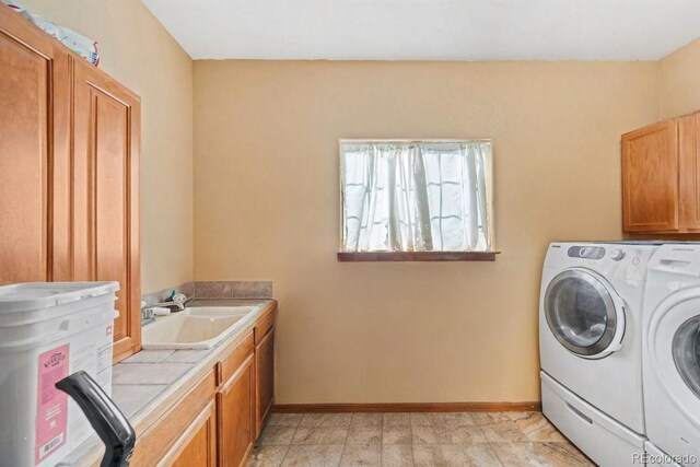 laundry room with washer and dryer, cabinet space, a sink, and baseboards