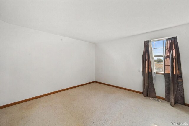 unfurnished room featuring carpet flooring, visible vents, and baseboards