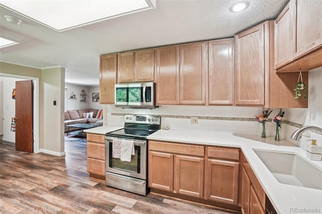 1213 S Taft Hill Rd, Fort Collins, CO 80521 - kitchen with stainless steel appliances, tasteful backsplash, light wood-type flooring, light countertops, and crown molding