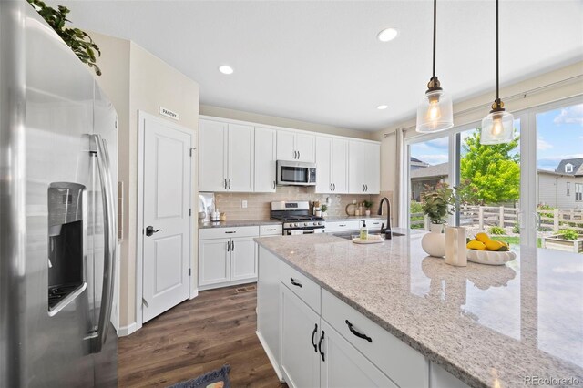 8261 Garden City Ave, Littleton, CO 80125 - kitchen featuring appliances with stainless steel finishes, dark wood-style floors, a sink, tasteful backsplash, and hanging light fixtures