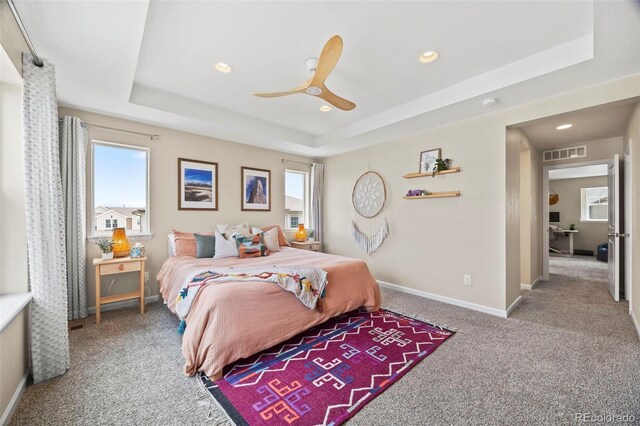 8261 Garden City Ave, Littleton, CO 80125 - bedroom with a tray ceiling, multiple windows, carpet flooring, recessed lighting, and baseboards