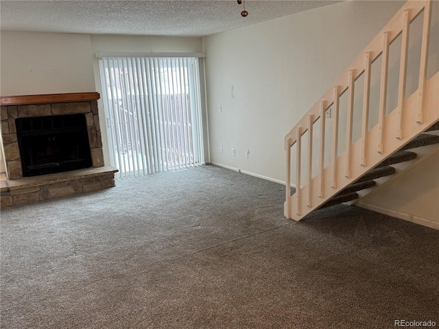 unfurnished living room with dark carpet, a fireplace, and a textured ceiling