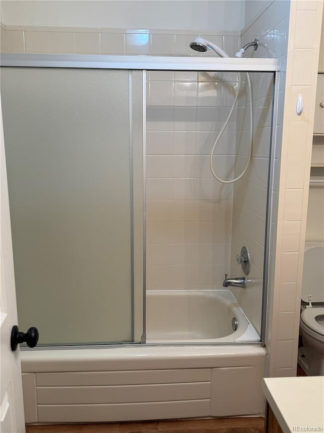 full bathroom with enclosed tub / shower combo, vanity, and toilet