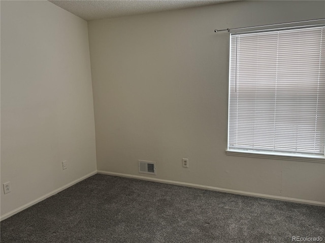 spare room with dark colored carpet and a textured ceiling