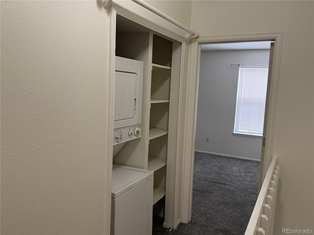 laundry room with dark colored carpet and stacked washer / drying machine