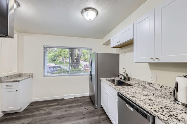5712 S Lowell Blvd, Littleton, CO 80123 - kitchen with appliances with stainless steel finishes, a sink, white cabinetry, dark wood-type flooring, and light stone countertops