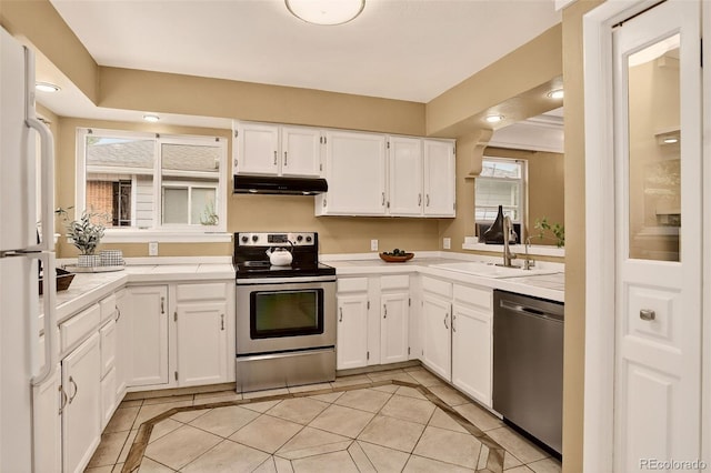3979 S Grant St, Englewood, CO 80113 - kitchen with stainless steel appliances, under cabinet range hood, inlaid floor details, light countertops, and light tile patterned flooring