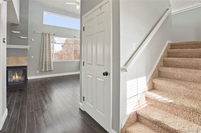 stairway featuring hardwood / wood-style floors, ceiling fan, and a tiled fireplace