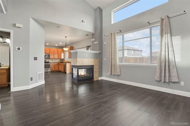 unfurnished living room with a fireplace, a high ceiling, and dark hardwood / wood-style floors