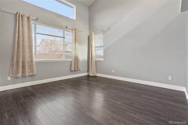 spare room featuring dark hardwood / wood-style flooring and a towering ceiling