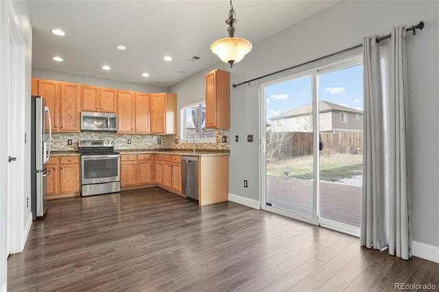 kitchen with appliances with stainless steel finishes, dark wood-type flooring, plenty of natural light, and pendant lighting