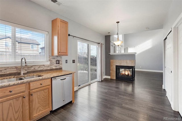 kitchen with dishwasher, backsplash, a tile fireplace, dark wood-type flooring, and sink