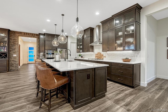 2159 Bellcove Dr, Castle Pines, CO 80108 - kitchen with wall chimney range hood, dark brown cabinets, dark wood finished floors, backsplash, and recessed lighting