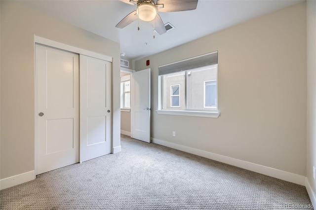 unfurnished bedroom with light colored carpet, a closet, and ceiling fan