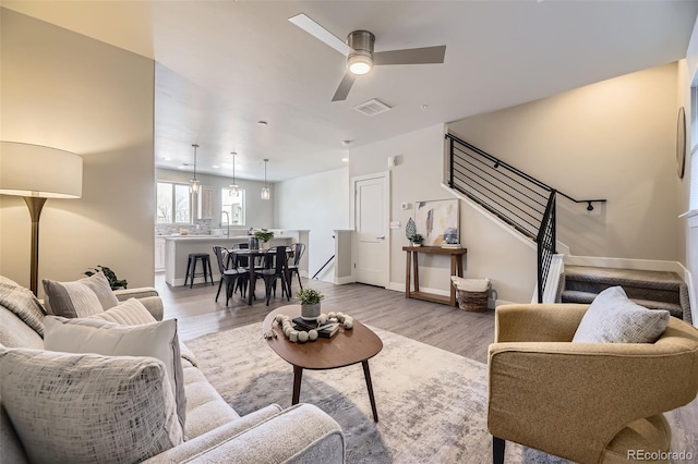 living room featuring ceiling fan, sink, and light hardwood / wood-style floors