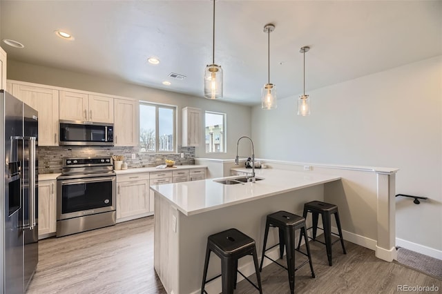 kitchen with appliances with stainless steel finishes, pendant lighting, white cabinetry, sink, and a breakfast bar area