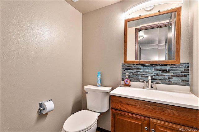 bathroom featuring vanity, toilet, and decorative backsplash