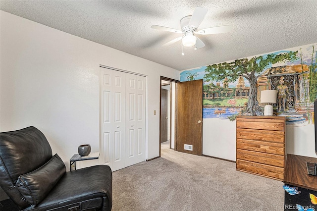 living area with light carpet, ceiling fan, and a textured ceiling