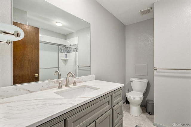 bathroom with a shower with door, vanity, tile patterned flooring, and toilet