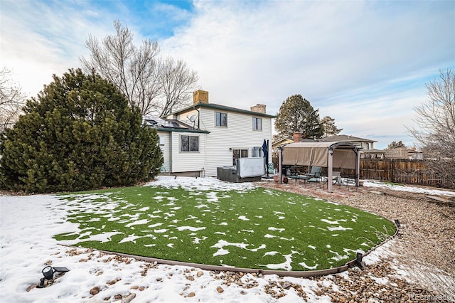 snow covered house with a gazebo, a hot tub, and a lawn