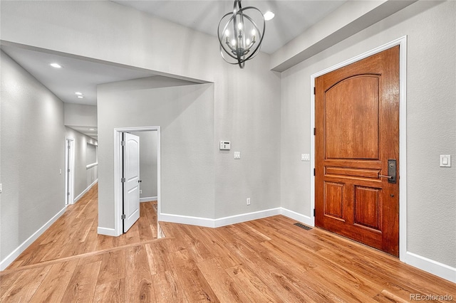 entrance foyer with light wood-style flooring, a chandelier, and baseboards