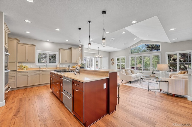 kitchen with open floor plan, light countertops, cream cabinetry, a center island with sink, and vaulted ceiling