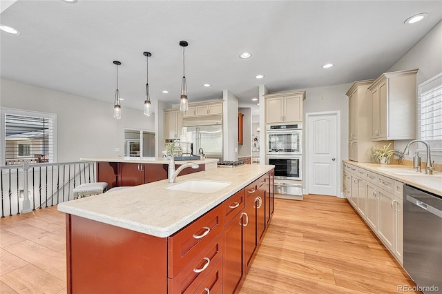 kitchen featuring a sink, stainless steel appliances, a warming drawer, a center island with sink, and recessed lighting
