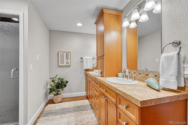 bathroom with baseboards, vanity, wood finished floors, and a textured wall