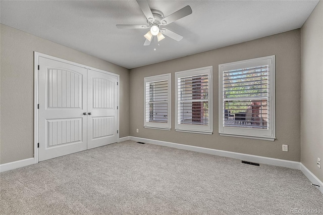 unfurnished bedroom featuring carpet flooring, a closet, baseboards, ceiling fan, and a textured ceiling