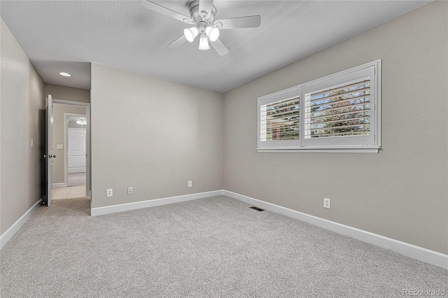 spare room with a ceiling fan, carpet, baseboards, and a textured ceiling