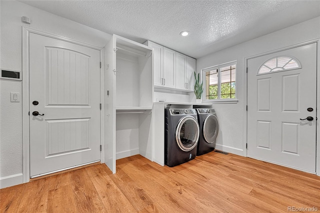 washroom featuring separate washer and dryer, light wood finished floors, a textured ceiling, cabinet space, and baseboards