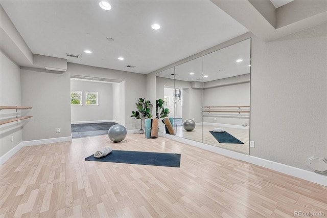 exercise area featuring wood finished floors, baseboards, and recessed lighting