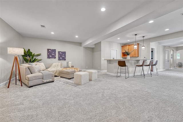 living area featuring light colored carpet, baseboards, recessed lighting, bar with sink, and arched walkways